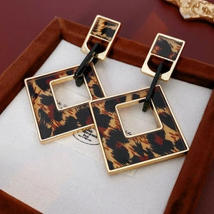 Detail of geometric leopard print earrings with gold frames in a velvet jewelry box
