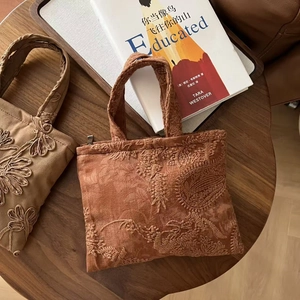 Detailed embroidery on vintage suede handbags with floral patterns on a wooden table