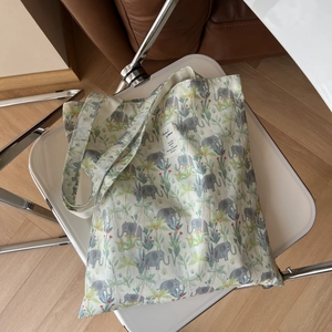 Detail shot of a canvas tote bag with green tropical plant and gray elephant patterns