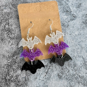 Halloween glitter bat earrings in silver, purple, and black acrylic on a display card
