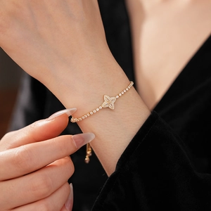 Close-up of golden clover bracelet with zircons and adjustable pull chain detail