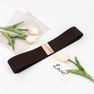Detail of dark brown elastic waist belt with rectangular golden metal buckle on a desk