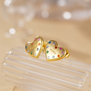 Macro detail of gold heart earrings with mama engraving and colorful zircon stones