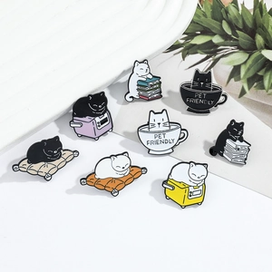 Detailed flat lay of colorful cartoon cat enamel pins featuring coffee and book motifs