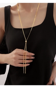 Macro shot of adjustable gold lariat snake chain necklace on a black garment