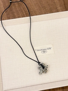 Detailed view of flower stone pendant on black cord over natural linen and wood background