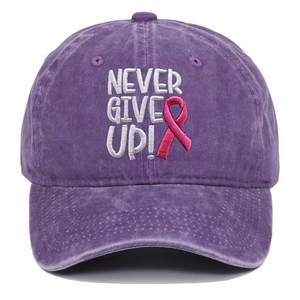 Detail der Stickerei 'NEVER GIVE UP!' und rosa Schleife auf lila gewaschener Baumwollkappe