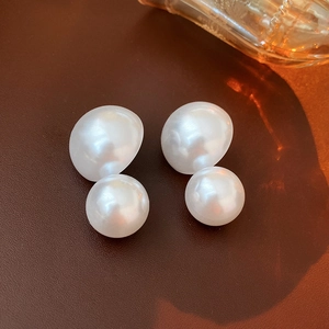 Close-up of elegant double pearl earrings with white luster on brown leather background