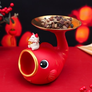Detail of red koi fish and white lucky cat figurine holding a golden tray with nuts