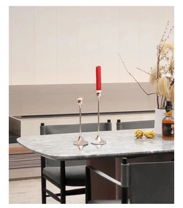 Detail van zilveren noordse kandelaars in twee hoogtes op een marmeren tafel