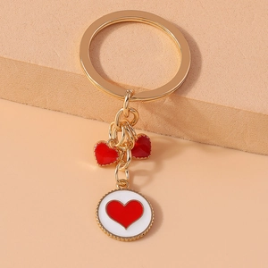 Detailed shot of golden keychain featuring red and white enamel heart charms on a sleek ring
