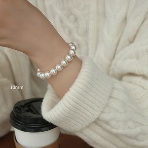 Detail shot of 10mm white pearls on a vintage elastic bracelet worn on the wrist