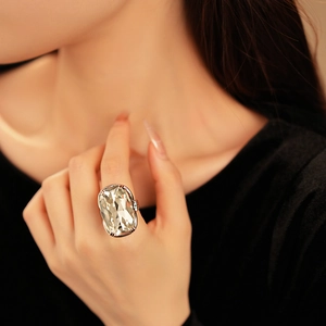 Close-up of a large cushion-cut crystal ring with gold prong setting on a hand