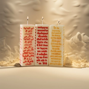 Three lit columnar pillar candle molds with engraved multilingual religious scriptures
