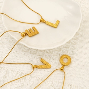 Gold LOVE letter pendant necklace with honeycomb texture on elegant white ceramic plate