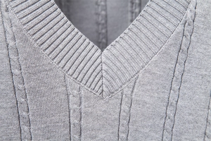 Detailansicht der grauen Strickweste mit V-Ausschnitt, Zopfmuster und Rippstrick-Textur