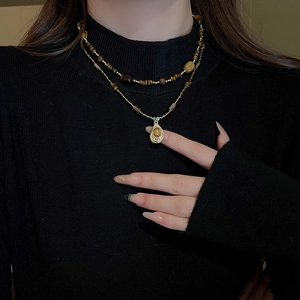 Détail d'un collier vintage double rang avec pendentif en pierre sur pull noir