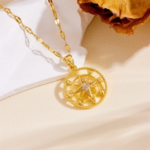 Detail of gold compass necklace with star pendant and inlaid zircons on a wavy chain
