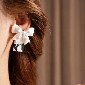 Vue détaillée de boucles d'oreilles avec nœud blanc et pendentif marbré noir