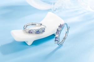 Detail view of silver hoop earrings with alternating purple and white cubic zirconia stones