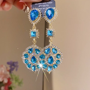 Macro shot of ethnic style gold earrings with blue crystals and sparkling tassels