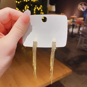 Détail de boucles d'oreilles pendantes dorées avec diamants et aiguilles en argent 925