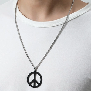 Close-up of a matte black peace sign pendant worn on a silver box chain over a white t-shirt
