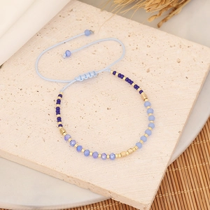 Macro shot of blue and purple beaded woven bracelet with adjustable cord and gold accents