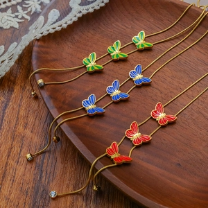 Close-up of enamel butterfly bracelets in gold finish displayed on a dark wooden tray