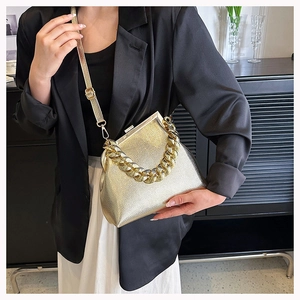 Detail of gold metallic crossbody bag with textured leather, chain strap, and retro clasp