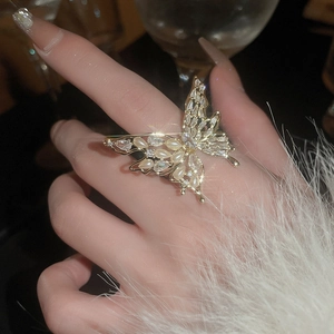 Close-up of golden butterfly ring with pearls and zircon crystals on a hand