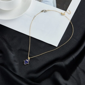 Detailed view of an 18K gold-plated Evil Eye necklace on black silk and book background
