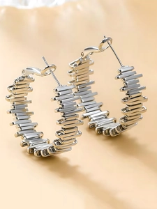 Macro shot of silver C-shaped earrings with industrial layered geometric metal plates