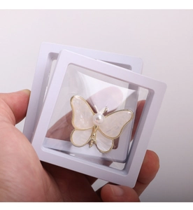 Macro shot of white butterfly brooch with pearls inside a PE film suspension jewelry box
