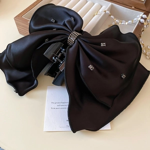 Détail d'une grande pince à cheveux en satin noir ornée de strass étincelants