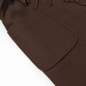 Détail d'un manteau marron en laine avec de grandes poches plaquées et des franges