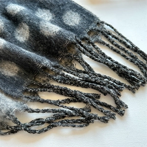 Close-up of soft cashmere-feel scarf detailing tassel fringe and white polka dot patterns