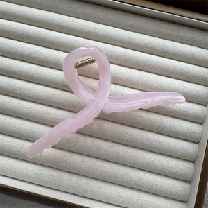Detail of pink marble textured hair claw clip with metal spring in a beige jewelry box