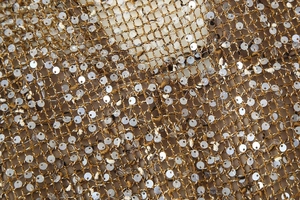 Gros plan sur tissu en maille dorée orné de paillettes argentées scintillantes