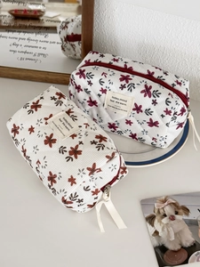 Macro detail of quilted corduroy makeup bags with red floral patterns and zip closure
