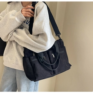 Detail of black corduroy crossbody bag featuring multi-pocket design and wide strap