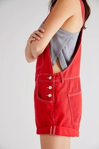 Detail view of red denim overalls with side buttons and contrast white stitching accents