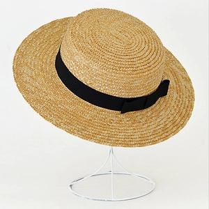 Classic straw boater hat with a black ribbon bow displayed on a metal stand