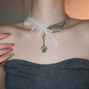 Détail du collier plume asymétrique avec cristaux et grand pendentif en forme de larme