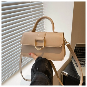 Detail view of a beige PU leather square bag featuring a distinctive metal D-ring buckle