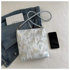 Detail of white jacquard bag with light blue and gold butterfly embroidery and blue strap