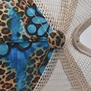 Macro detail showing leopard print fabric and blue polka dot patterns on a mesh baseball cap