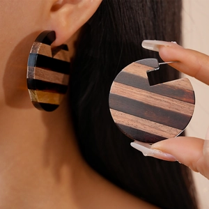 Detailed view of C-shaped striped wood earrings showing texture and splicing design