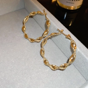 Close-up of golden twist hoop earrings with a metallic spiral texture in a velvet box