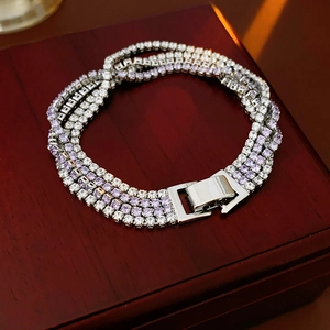 Vue macro d'un bracelet tennis à quatre rangées avec cristaux violets et blancs sur un coffret